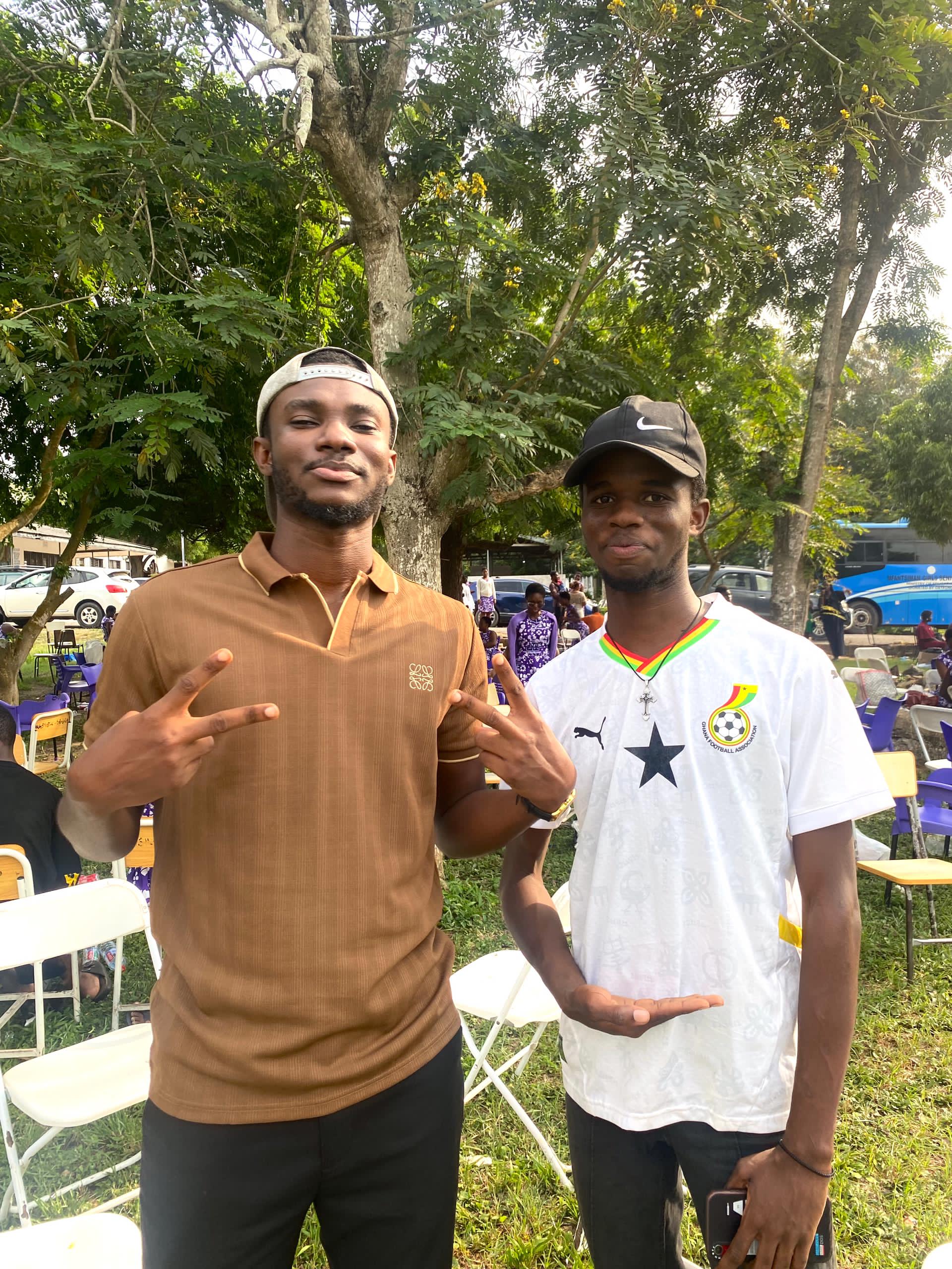 Two Kings & Priests members embrace against a pink backdrop, eyes closed and smiling in gratitude.