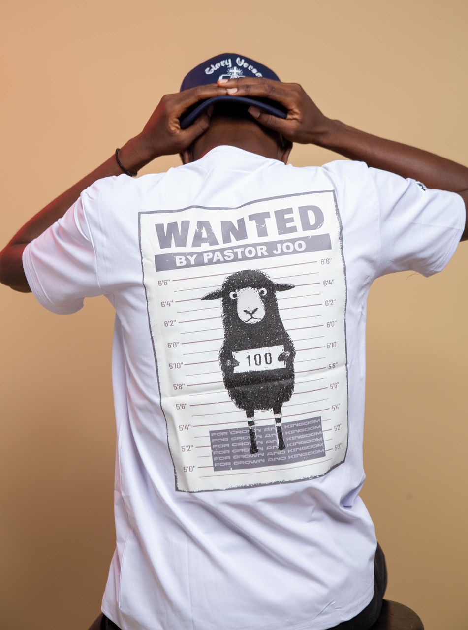 A Kings & Priests performer poses on one leg before a green backdrop wearing a pink crop top reading “Sorry boys, Daddy said I can’t date,” black shorts, rainbow-detailed socks, and expressive accessories.